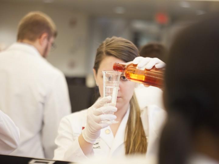 Student pours liquid into beaker during a lab